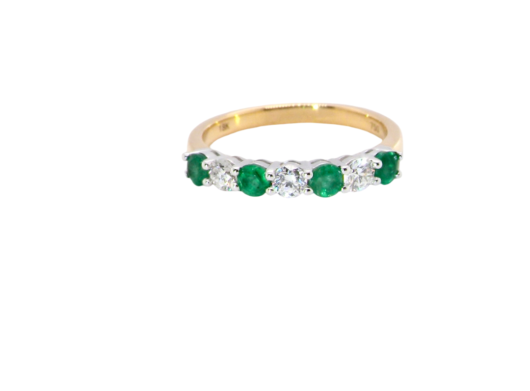 A NEW seven stone half hoop eternity ring. Set with four round emeralds, each 2.8mm (total 0.40 carats)
