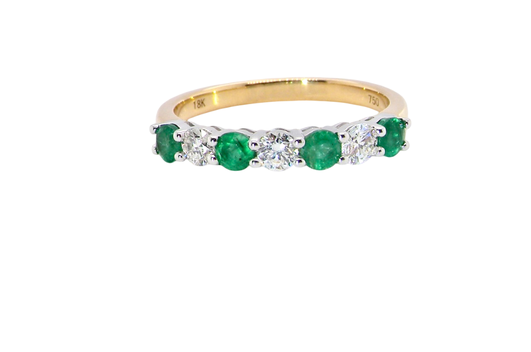 A NEW seven stone half hoop eternity ring. Set with four round emeralds, (total 0.40 carats)