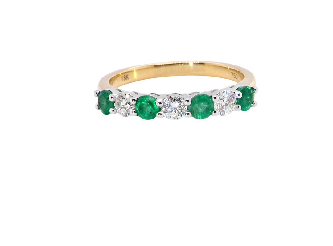 A NEW seven stone half hoop eternity ring. Set with four round emeralds, (total 0.40 carats)