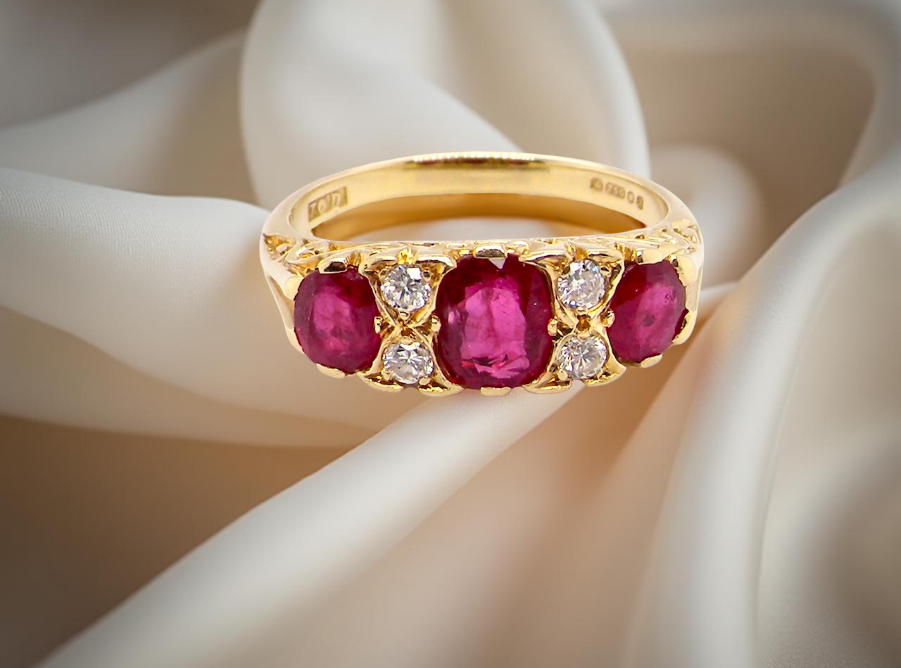 Gold ring with ruby gemstones and small diamonds on a soft white background