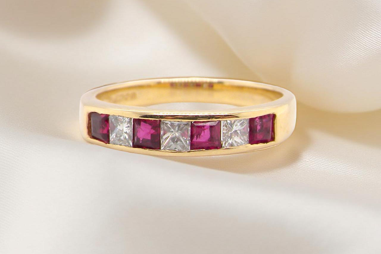 A gold half-hoop eternity ring set with rubies and diamonds.