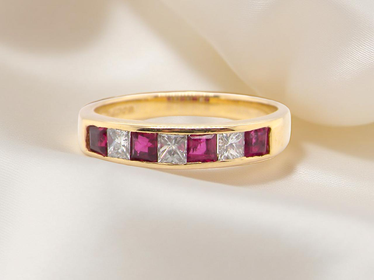 A gold half-hoop eternity ring set with rubies and diamonds.