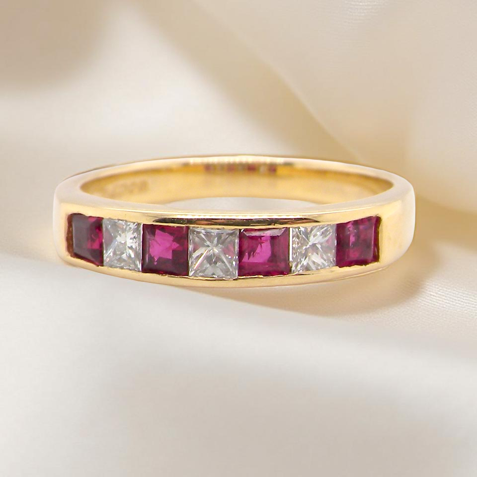 A gold half-hoop eternity ring set with rubies and diamonds.