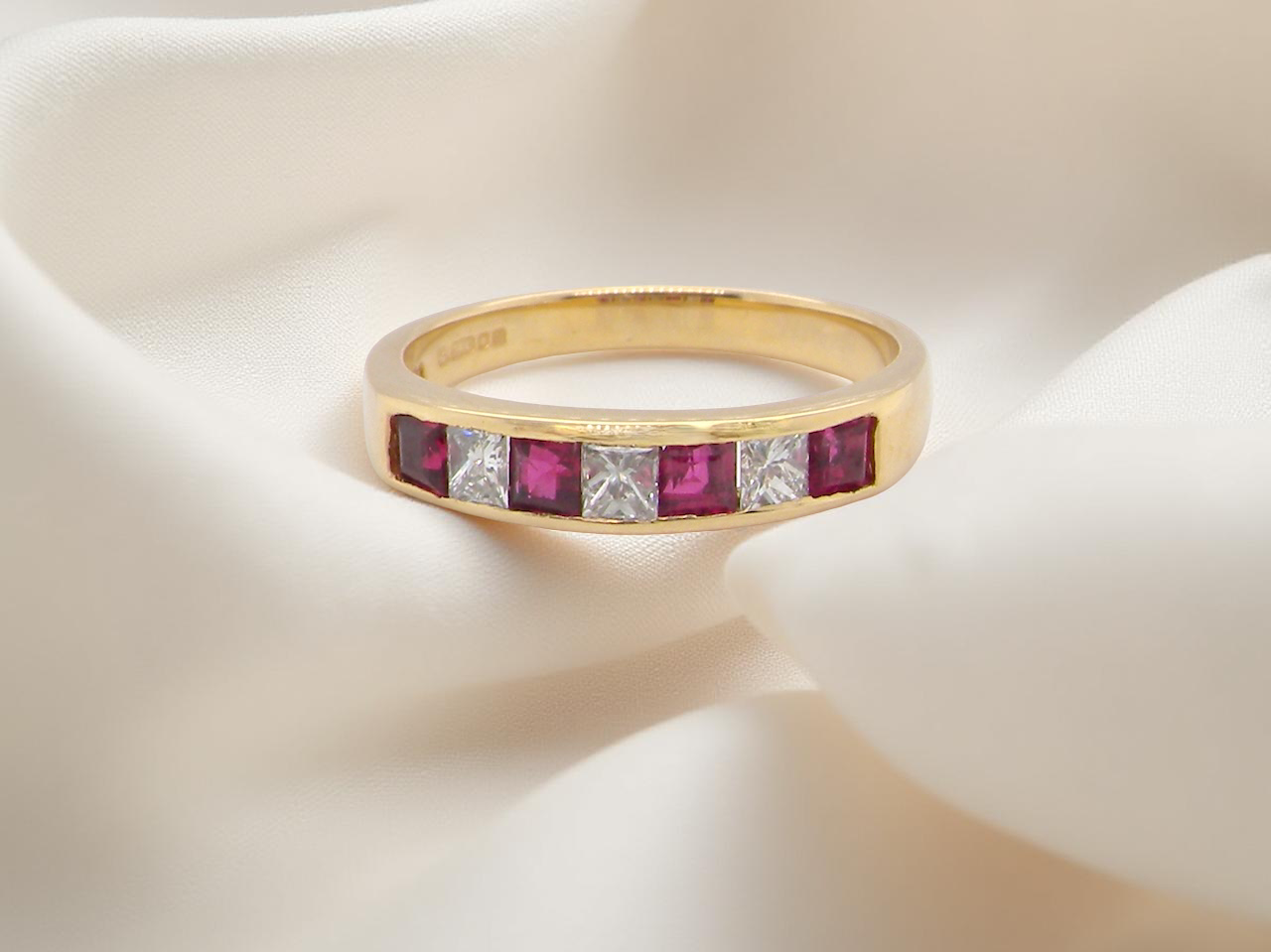 A beautiful gold half-hoop eternity ring with alternating rubies and diamonds.