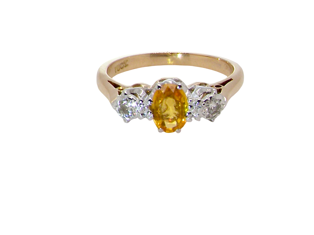 A yellow gold ring with a central oval yellow gemstone and two round clear accent stones on either side, shown on a plain white background.