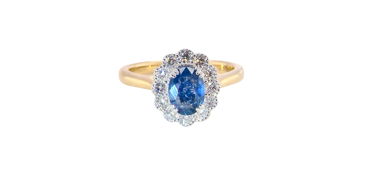 A beautiful cluster ring featuring an oval-cut mid to dark blue sapphire measuring 7 × 5 mm (approximately ¾ carat).