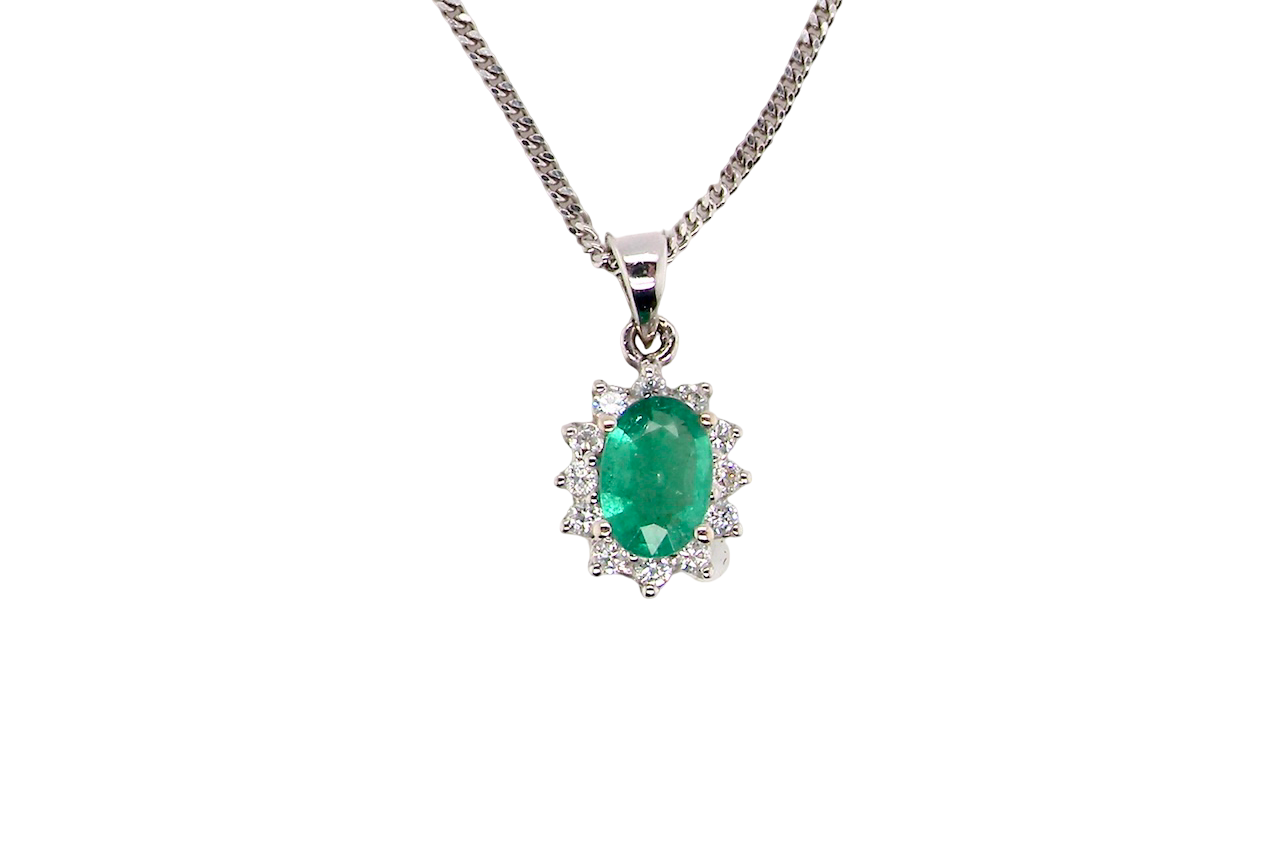 A beautiful traditional cluster pendant featuring a vibrant oval-cut emerald