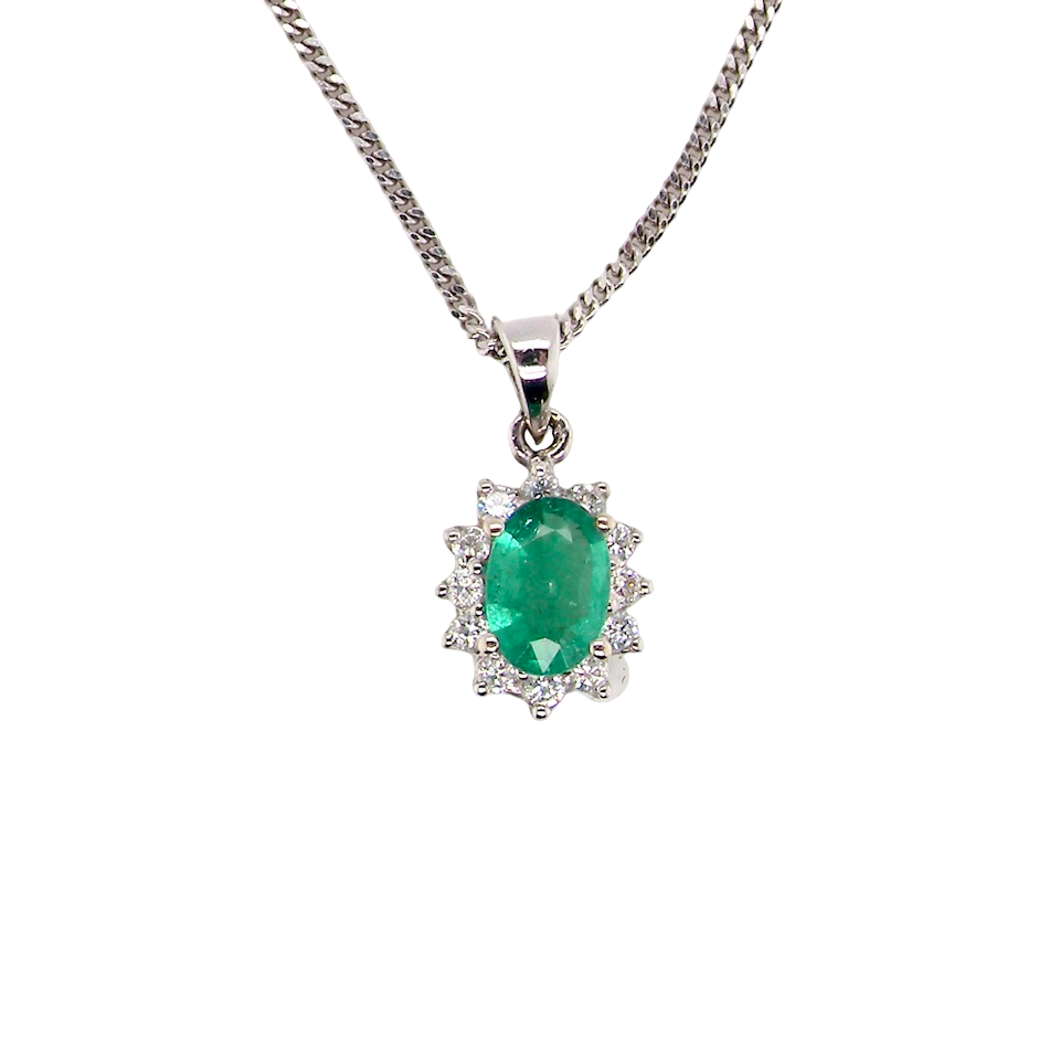 A beautiful traditional cluster pendant featuring a vibrant oval-cut emerald