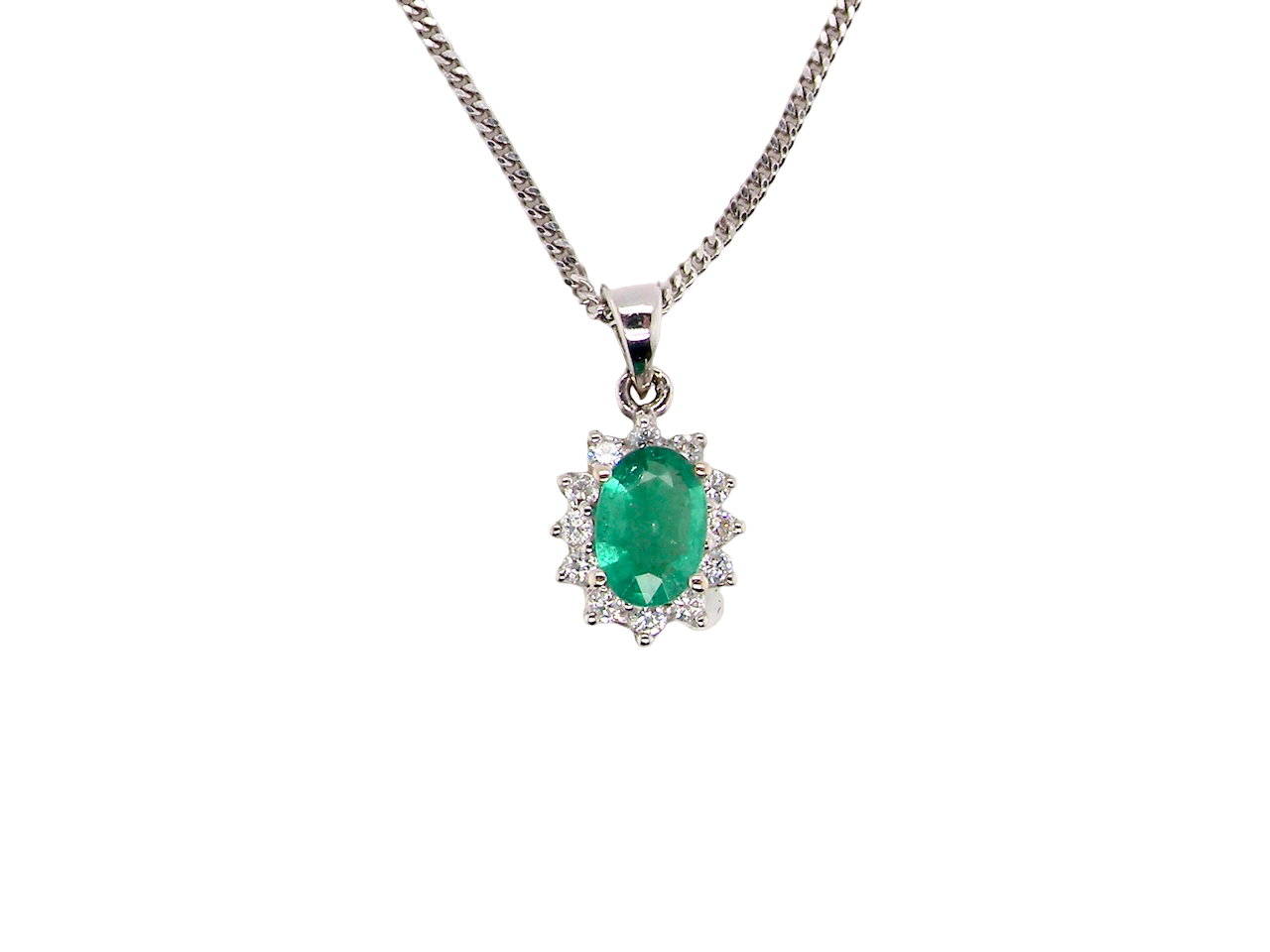 A beautiful traditional cluster pendant featuring a vibrant oval-cut emerald