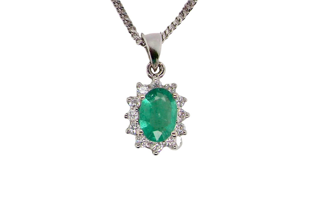 A beautiful traditional cluster pendant featuring an oval-cut emerald