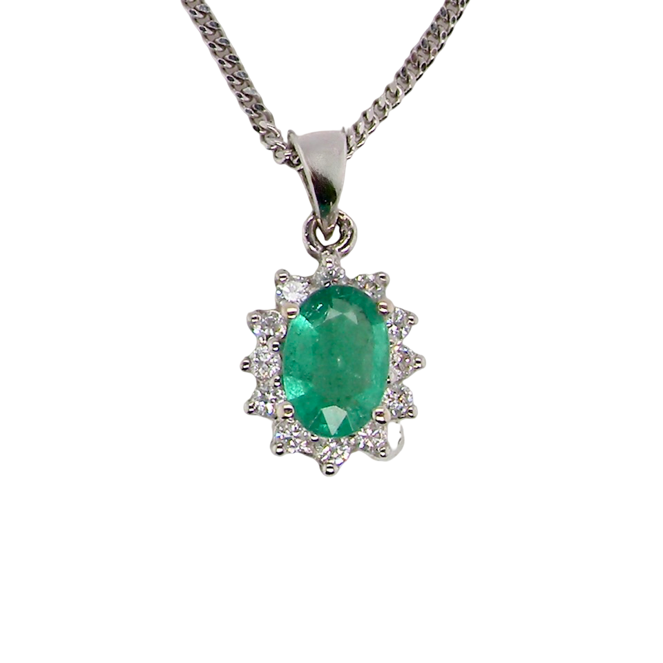 A beautiful traditional cluster pendant featuring an oval-cut emerald