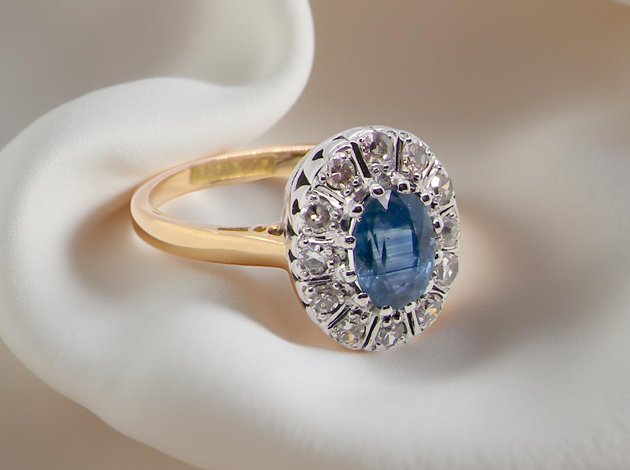 A beautiful cluster ring featuring an oval mid-blue sapphire