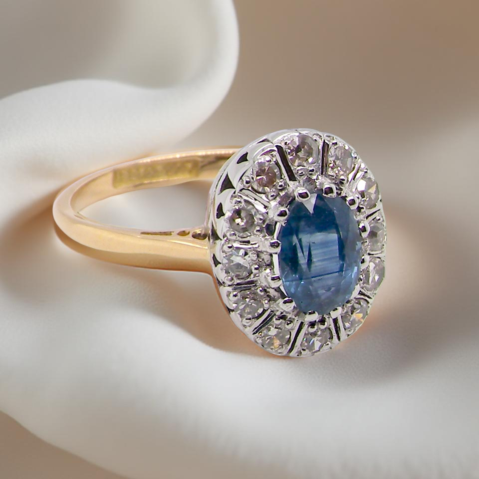 A beautiful cluster ring featuring an oval mid-blue sapphire