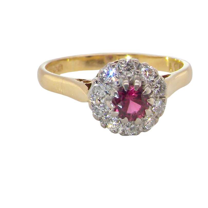 A yellow gold ring featuring a central round pink gemstone surrounded by a halo of small clear stones, set against a plain white background.
