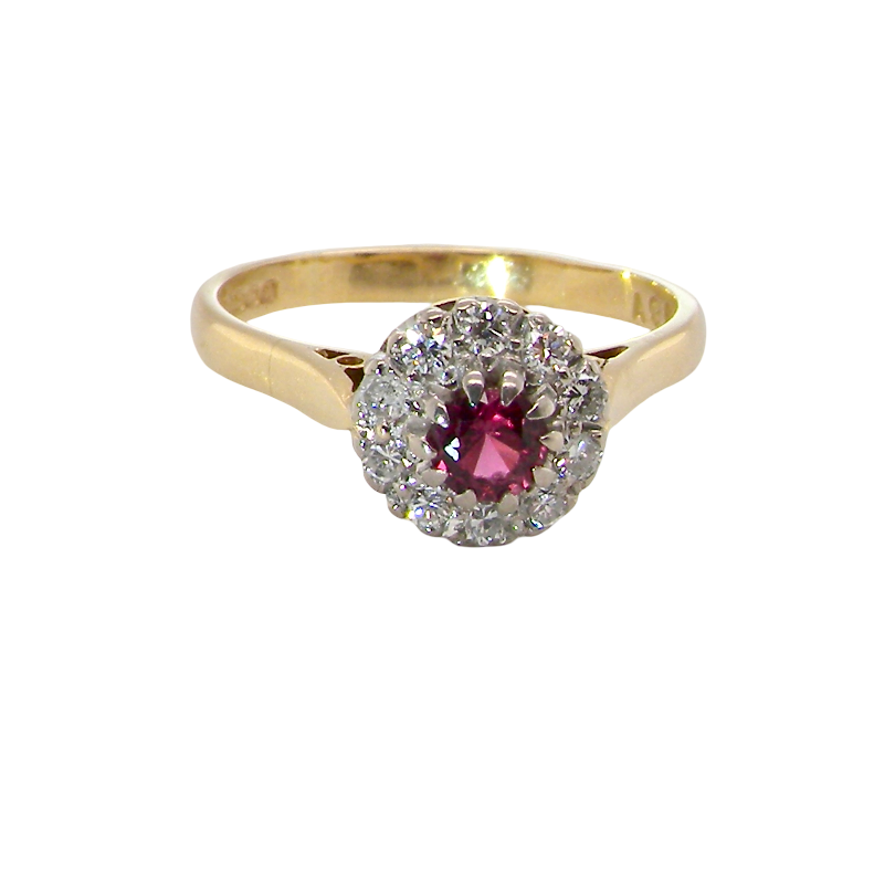 A yellow gold ring featuring a central round pinkish-red ruby gemstone surrounded by a halo of small clear stones, set against a plain white background.
