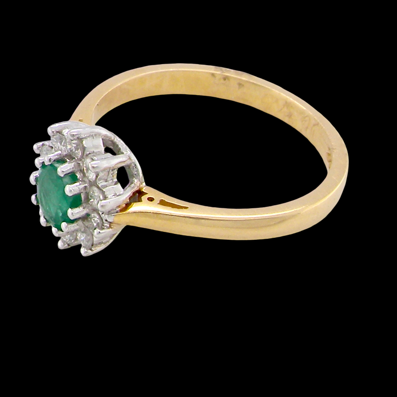 A classic cluster ring. Features to the centre a round emerald, comlimented by an outer halo of brilliant cutdiamonds