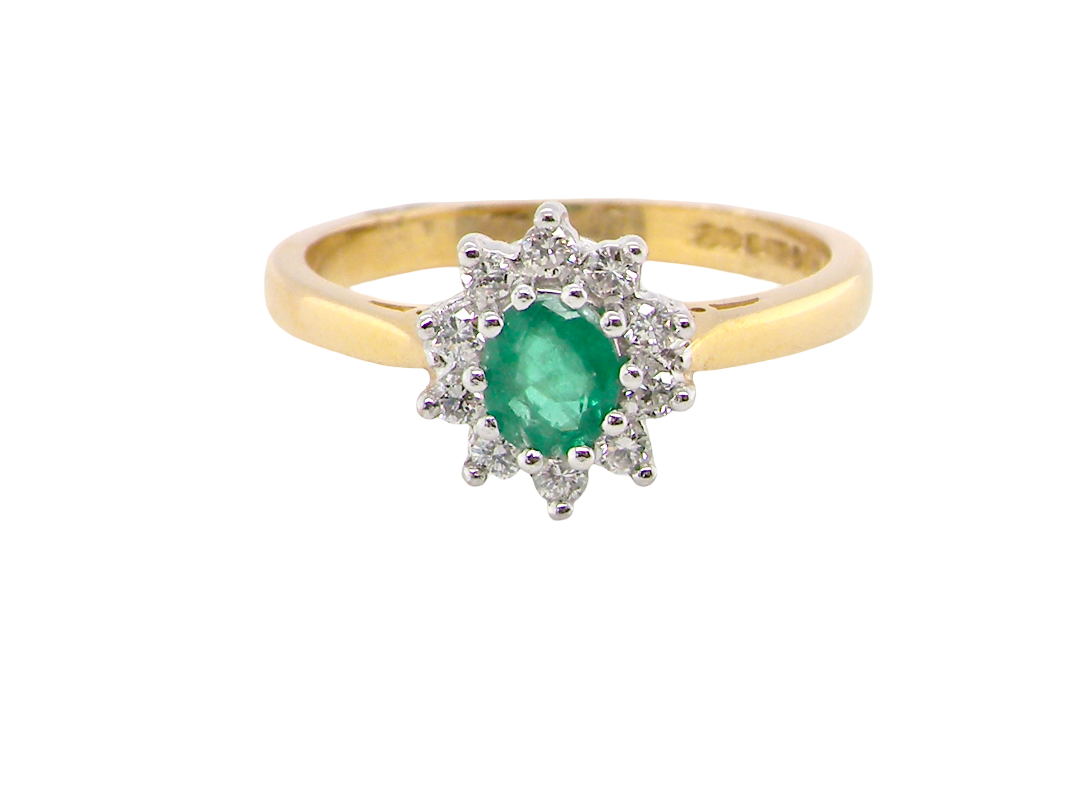 A classic cluster ring. Features to the centre a round emerald, comlimented by brilliant cut white diamonds