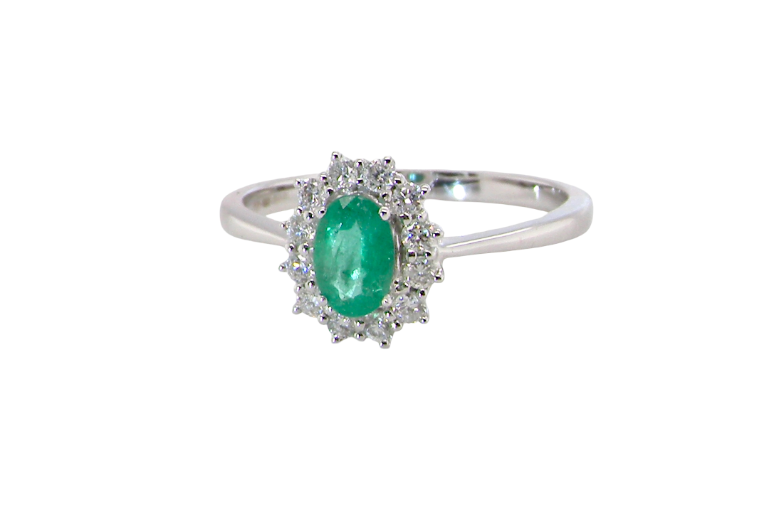 A classic cluster ring set with an oval cut emerald centre stone, measures 6x4mm, grass green colour.
Complimented by an outer halo of twelve brilliant cut white diamonds, each 1.7mm