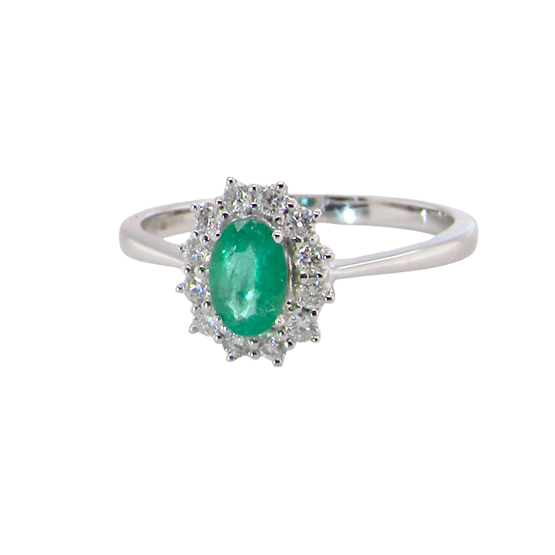 A classic cluster ring set with an oval cut emerald centre stone, measures 6x4mm, grass green colour.
Complimented by an outer halo of twelve brilliant cut white diamonds, each 1.7mm