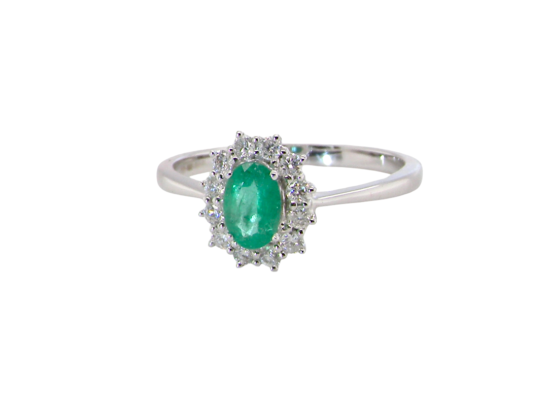 A classic cluster ring set with an oval cut emerald centre stone, measures 6x4mm, grass green colour.
Complimented by an outer halo of twelve brilliant cut white diamonds, each 1.7mm