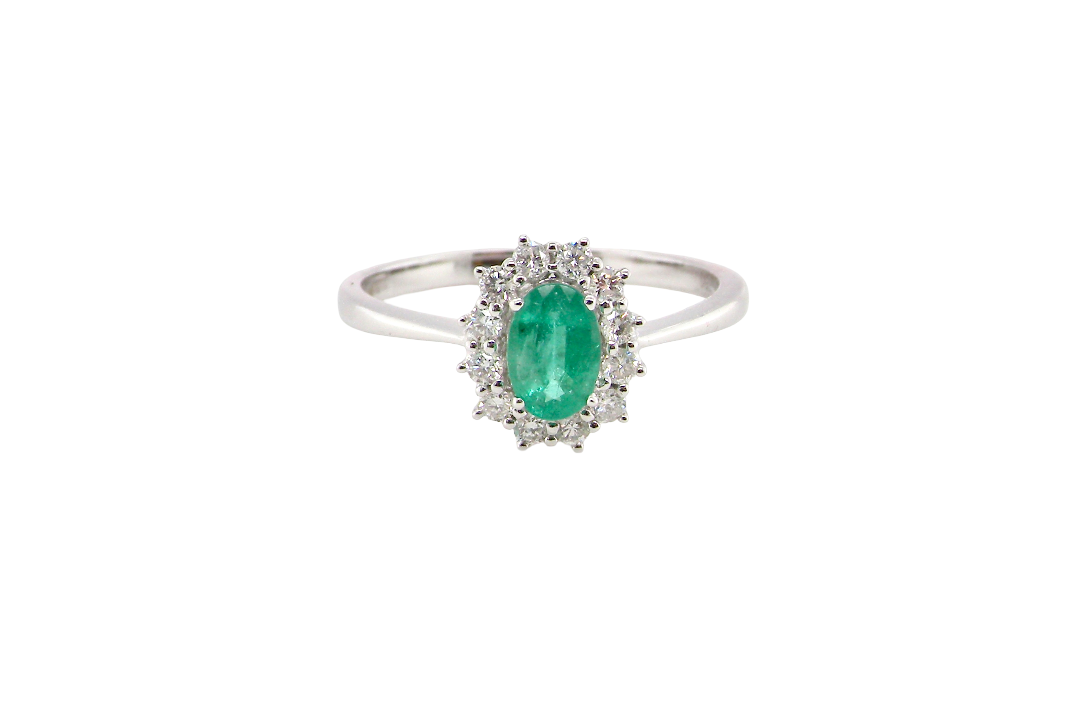 A classic cluster ring set with an oval cut emerald centre stone, measures 6x4mm, grass green colour.
Complimented by an outer halo of twelve brilliant cut white diamonds, each 1.7mm (total est at 0.25 carats)