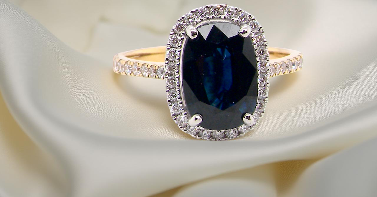 A cluster ring featuring a captivating ink-black blue sapphire, A