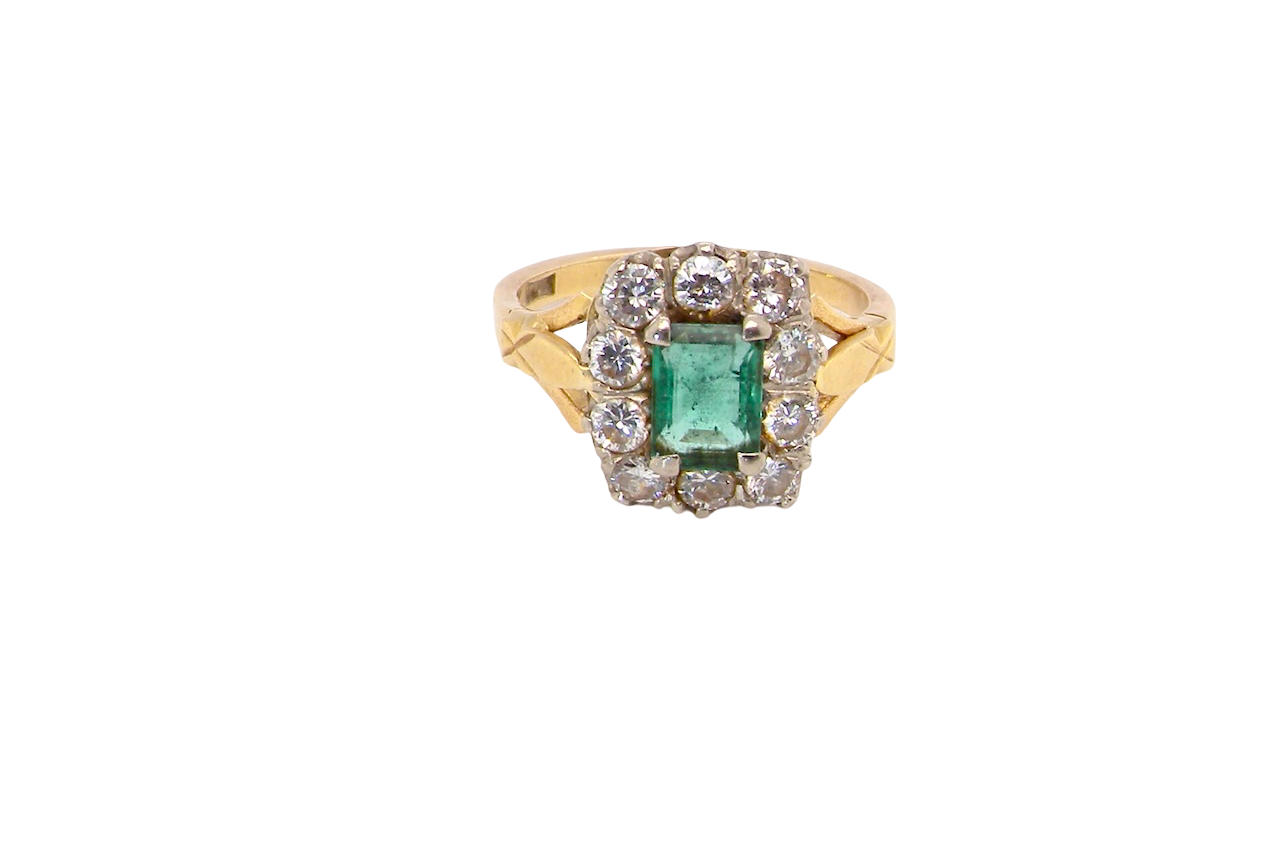 A cluster ring that features a rectangular emerald centre stone, 7x5mm . Deep green colour, natural inclusions that can be seen under an eye glass, but not easily visible via the naked eye.
