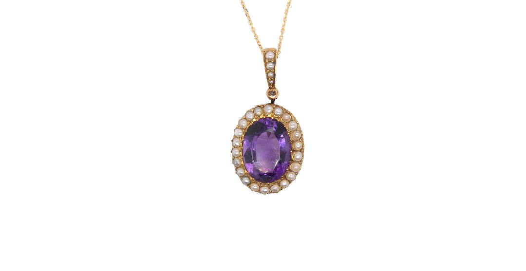 An oval pendant necklace featuring a central purple amethyst gemstone surrounded by a halo of small clear stones, set in yellow gold and suspended from a delicate gold chain against a plain white background.