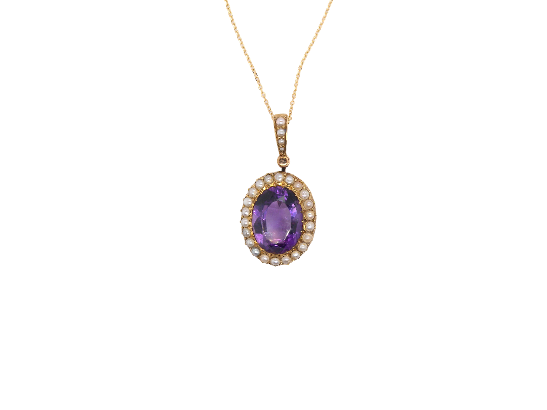 An oval pendant necklace featuring a central purple amethyst gemstone surrounded by a halo of small clear stones, set in yellow gold and suspended from a delicate gold chain against a plain white background.