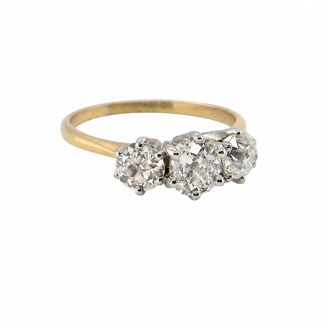 A vintage-style three-stone diamond ring with a yellow gold band and silver-toned settings, shown on a plain white background.