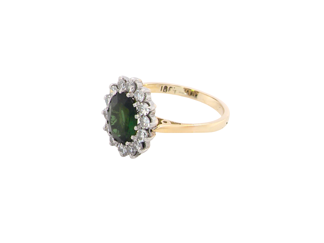A fine and impressive vintage cluster ring, centred with a striking oval-cut deep dark green tourmaline, measuring 9 x 7mm and estimated to weigh approximately 2.00 carats. side