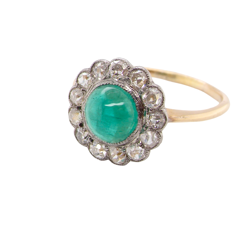 An antique-style ring featuring a round green emerald-cut center stone surrounded by a halo of small clear stones, set on a yellow gold band.