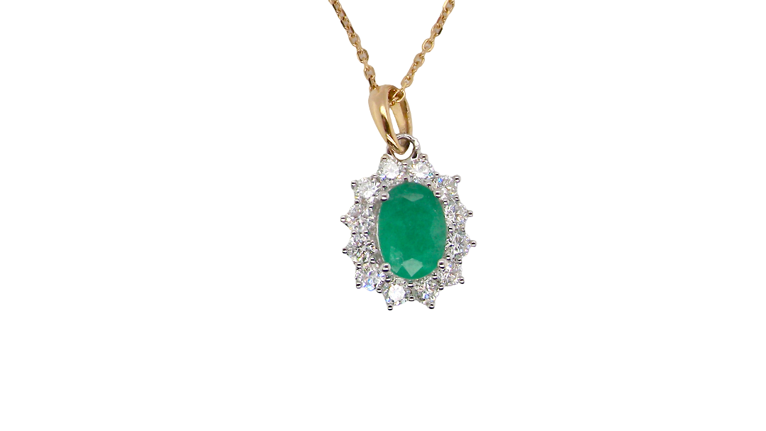 A fine cluster pendant. Features at the centre an oval cut emerald, measures 7.5x5mm (est one carat). Dark green hue, natural inclusions.
