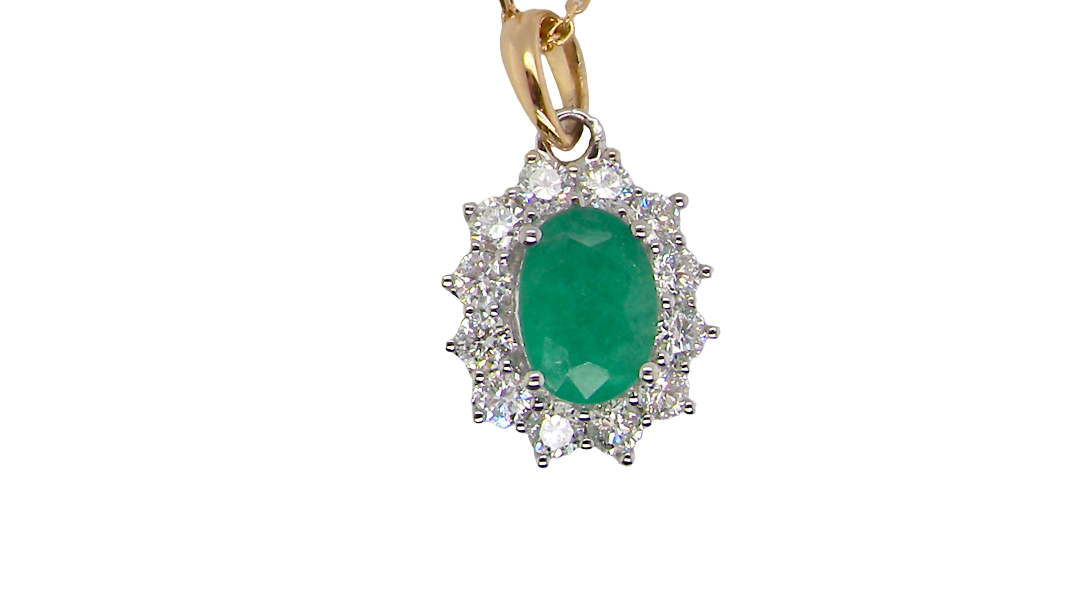 A fine cluster pendant. Features at the centre an oval cut emerald, measures 7.5x5mm (est one carat). natural inclusions.