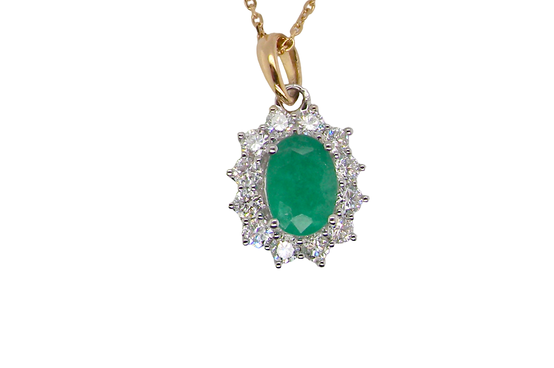 A fine cluster pendant. Features at the centre an oval cut emerald, measures 7.5x5mm (est one carat). natural inclusions.