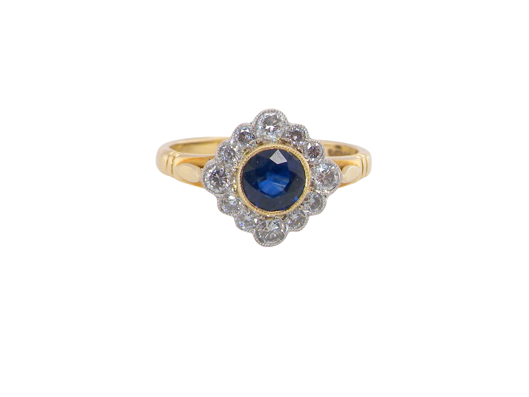 A fine cluster ring featuring to the centre a round dark blue sapphire, 5mm diameter (0.50 carats) mille grain setting.