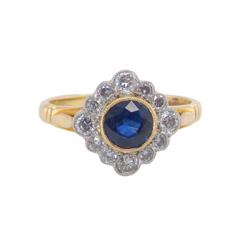 A fine cluster ring featuring to the centre a round dark blue sapphire, 5mm diameter mille grain setting.