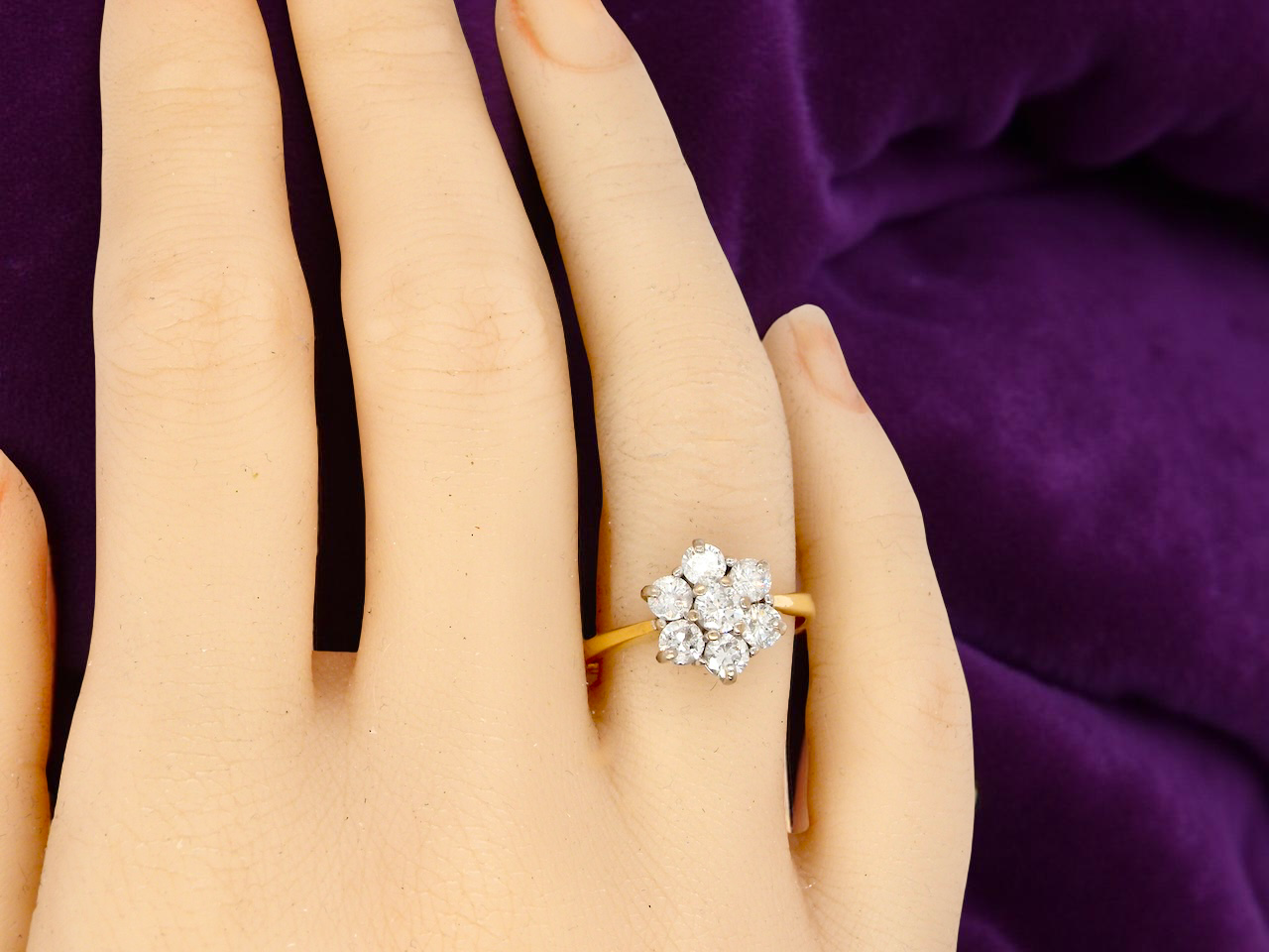 Gold and diamond ring on a hand with a purple background