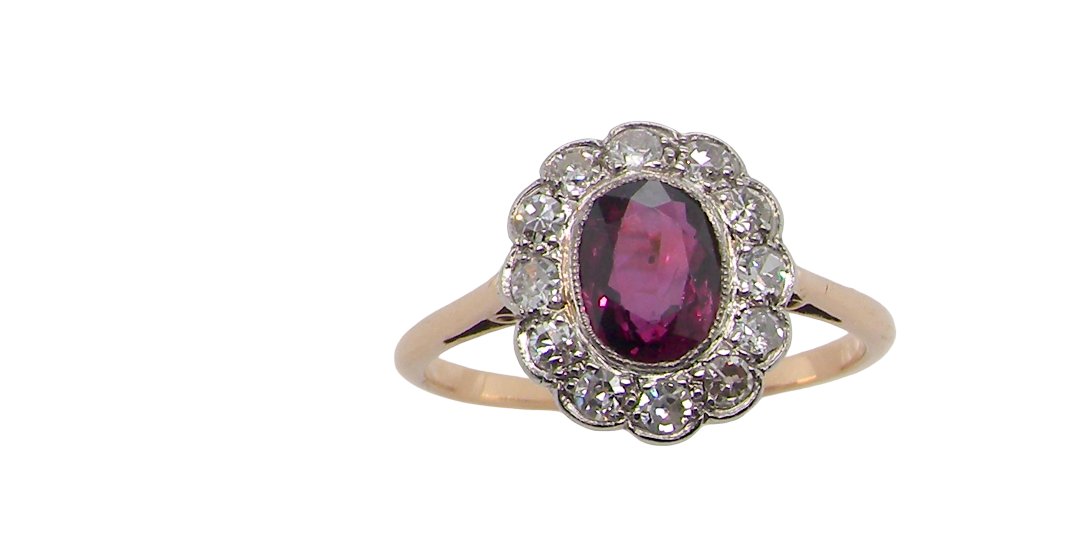 A fine early 20th century cluster ring featuring to the centre an oval ruby, 6x5mm, deep burgundy red colour, mille grain setting. (est 1.02 carats)