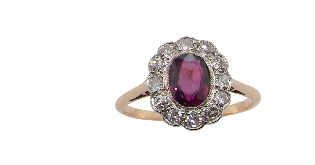 A fine early 20th century cluster ring featuring to the centre an oval ruby, 6x5mm, deep burgundy red colour, mille grain setting. (est 1.02 carats)