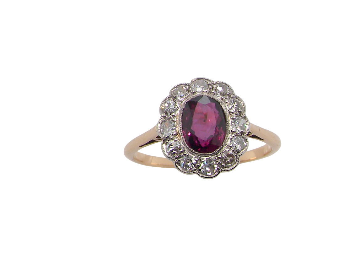 A fine early 20th century cluster ring featuring to the centre an oval ruby, 6x5mm, deep burgundy red colour, mille grain setting. (est 1.02 carats)