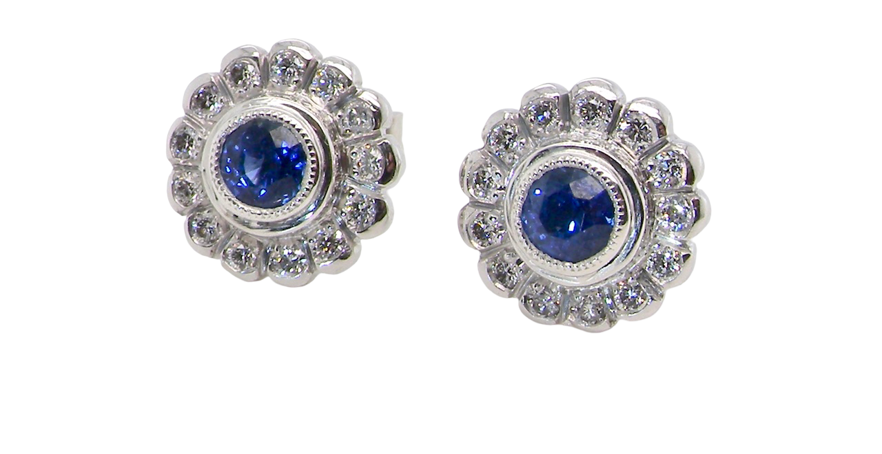 A fine pair of 18 carat white gold sapphire and diamond cluster earrings.
Each earring is set with a central round sapphire measuring approximately 3.4mm in diameter,