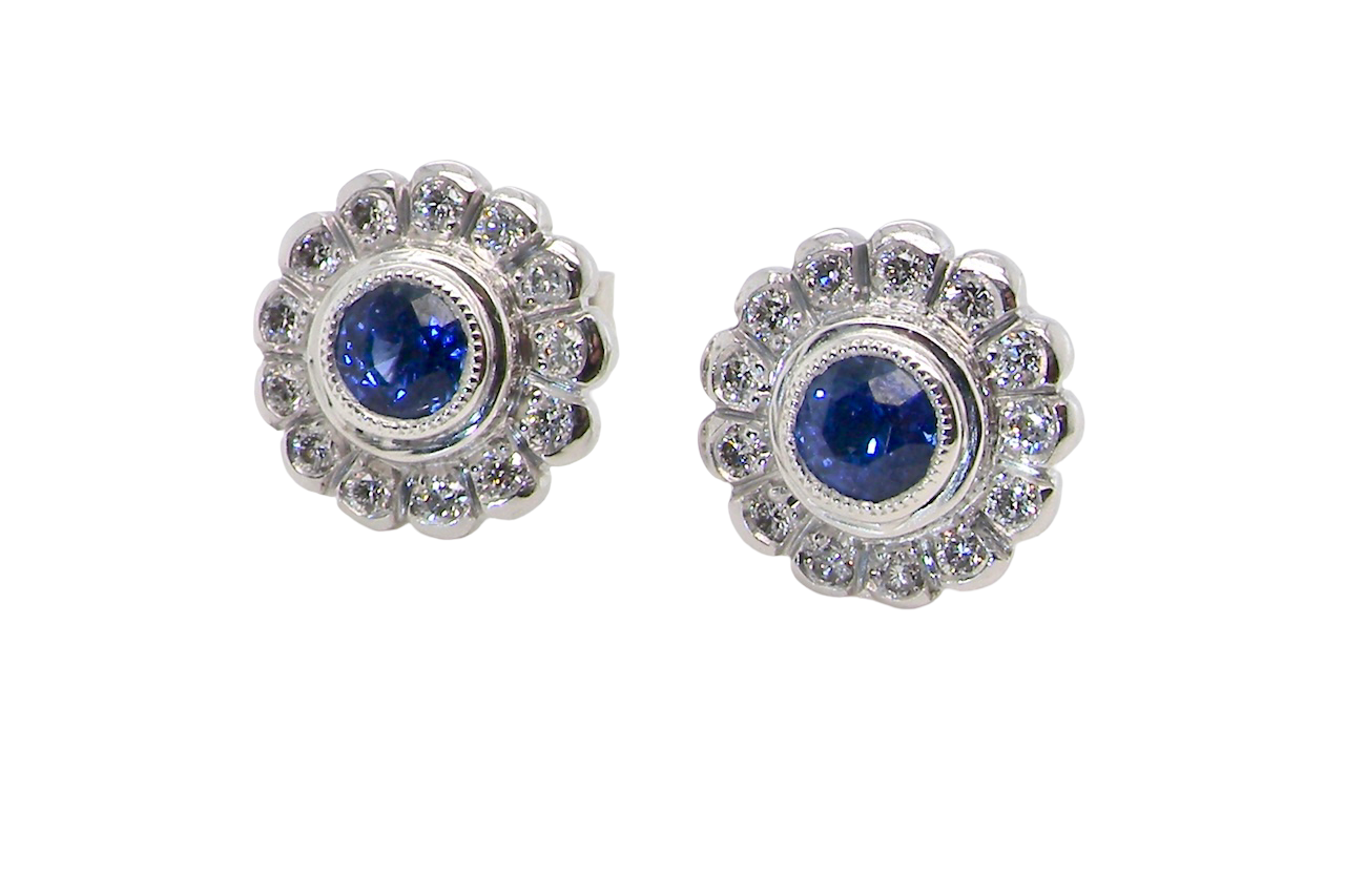 A fine pair of 18 carat white gold sapphire and diamond cluster earrings.
Each earring is set with a central round sapphire measuring approximately 3.4mm in diameter,
