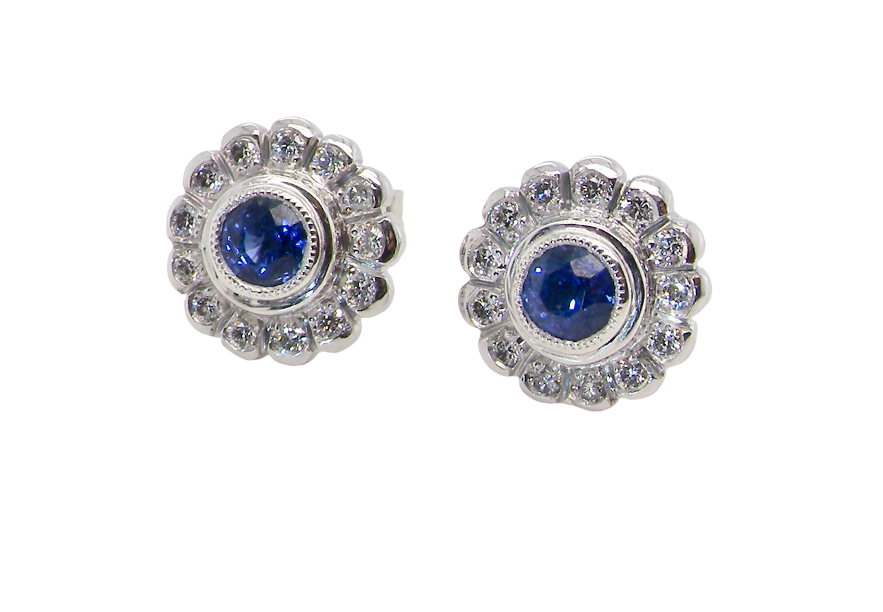 A fine pair of 18 carat white gold sapphire and diamond cluster earrings.
Each earring is set with a central round sapphire measuring approximately 3.4mm in diameter,