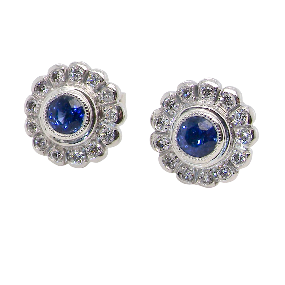 A fine pair of 18 carat white gold sapphire and diamond cluster earrings.
Each earring is set with a central round sapphire measuring approximately 3.4mm in diameter,