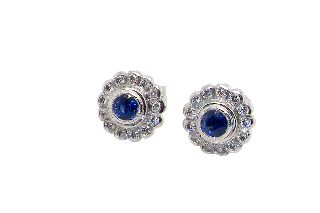A fine pair of 18 carat white gold sapphire and diamond cluster earrings.
Each earring is set with a central round sapphire measuring approximately 3.4mm in diameter, estimated at 0.15ct,