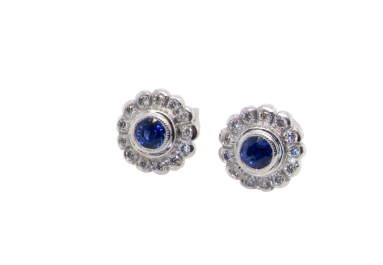 A fine pair of 18 carat white gold sapphire and diamond cluster earrings.
Each earring is set with a central round sapphire measuring approximately 3.4mm in diameter, estimated at 0.15ct,