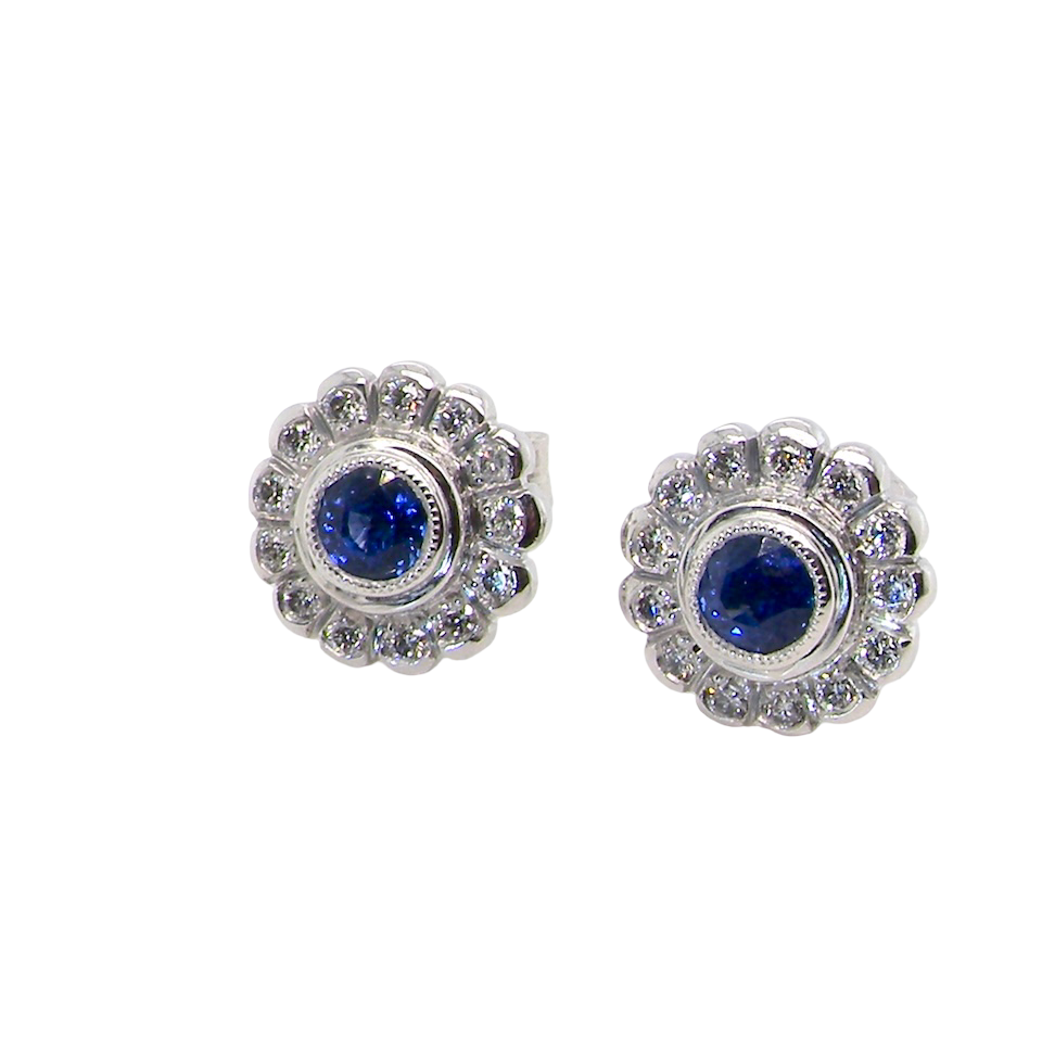 A fine pair of 18 carat white gold sapphire and diamond cluster earrings.
Each earring is set with a central round sapphire measuring approximately 3.4mm in diameter, estimated at 0.15ct,