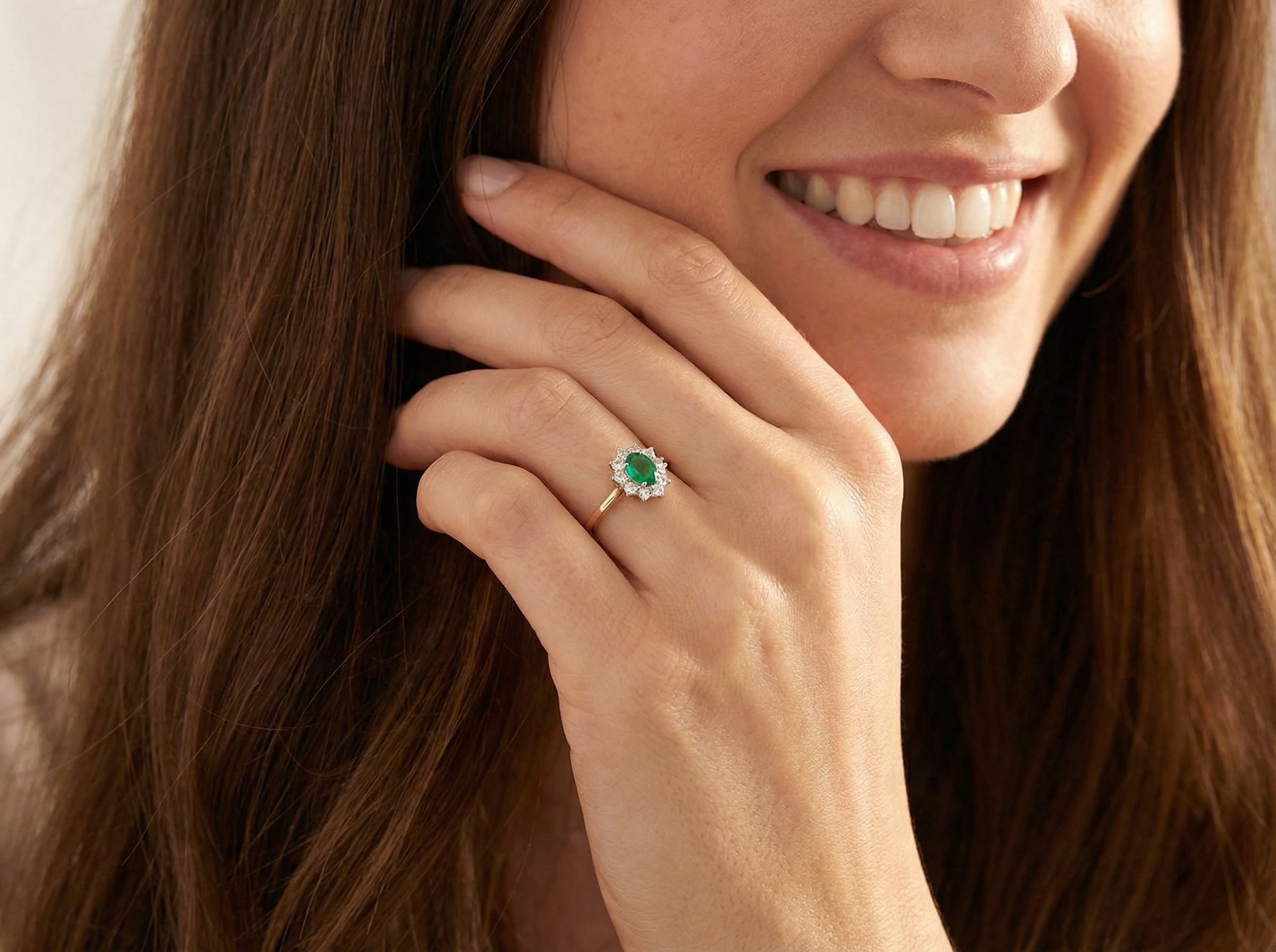 A fine traditional emerald and diamond cluster ring, featuring a vibrant oval-cut emerald to the centre measuring approximately 7 × 5 mm model