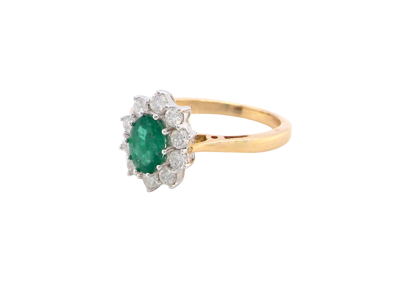 A fine traditional emerald and diamond cluster ring, featuring a vibrant oval-cut emerald to the centre measuring approximately 7 × 5 mm side